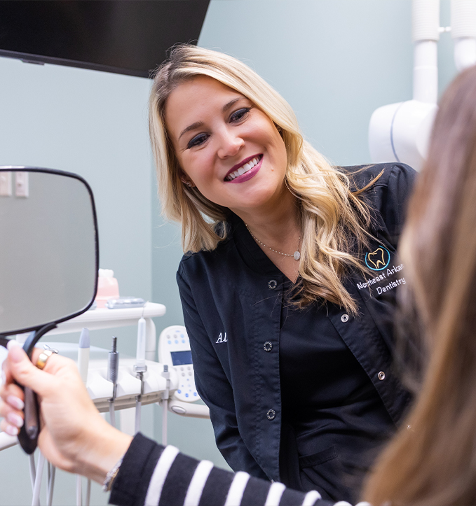 Woman in denim jacket smiling after cosmetic dentistry in Jonesboro