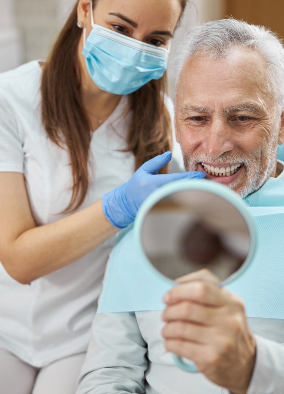 Senior dental patient admiring his smile in a mirror