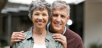 Senior man and woman smiling and hugging