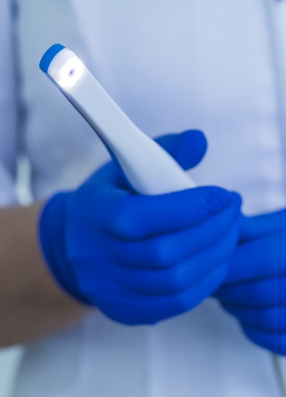 Dental team member holding a thin white intraoral camera