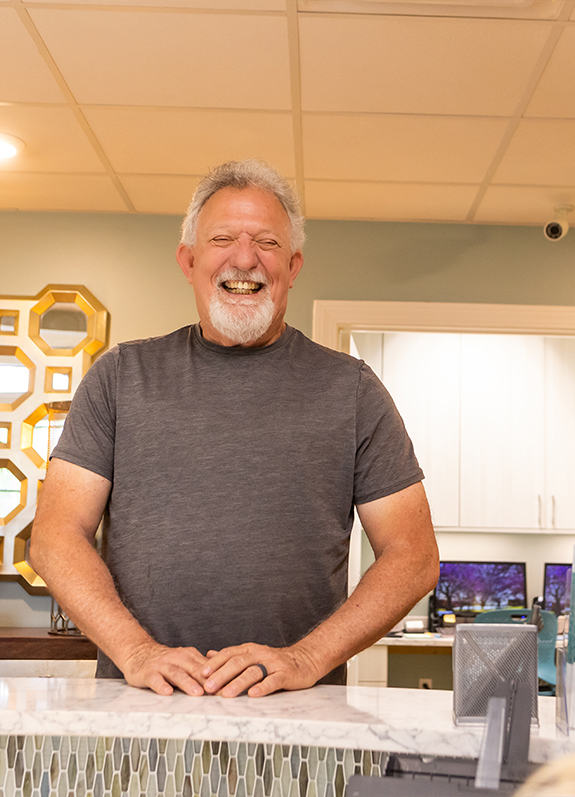 Smiling man shaking hands with person across desk