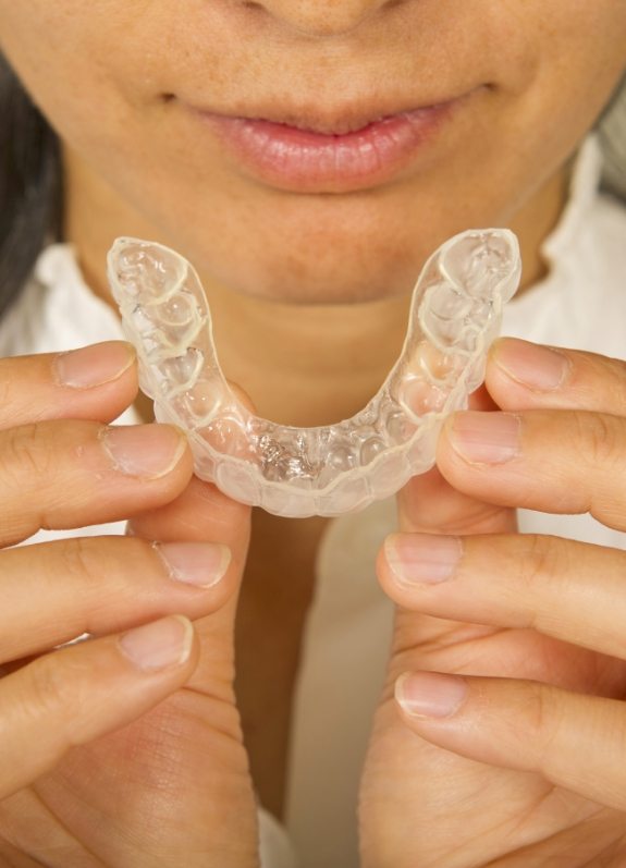 Close up of woman holding an Invisalign aligner