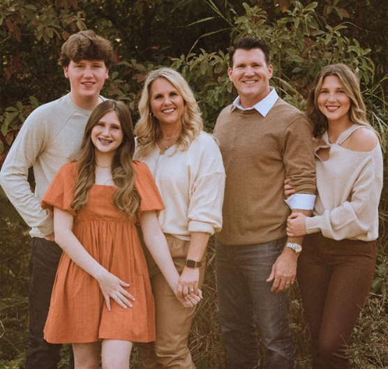 Doctor Spades smiling outdoors with his wife and three children