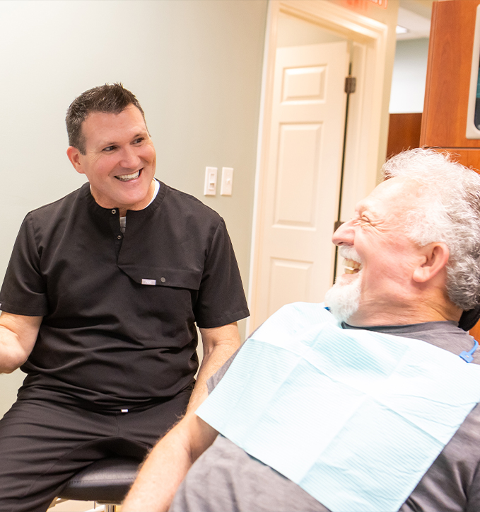 Senior couple hugging and smiling outdoors after replacing missing teeth in Jonesboro