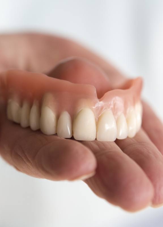 Hand holding a full upper denture