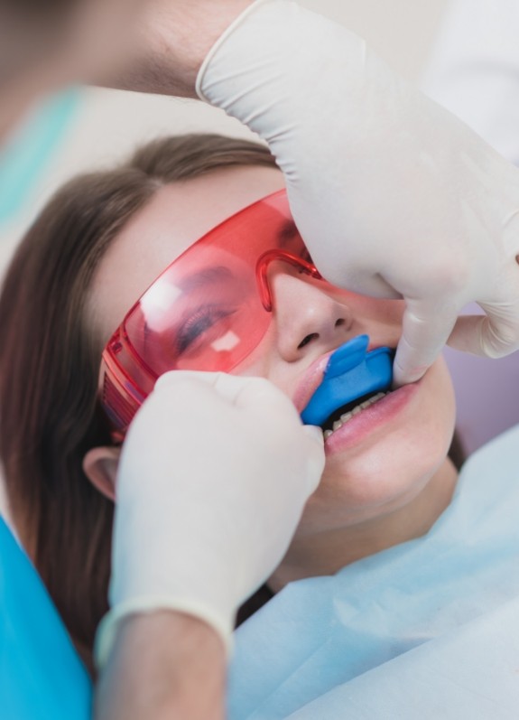 Young woman in dental chair having fluoride trays placed over her teeth